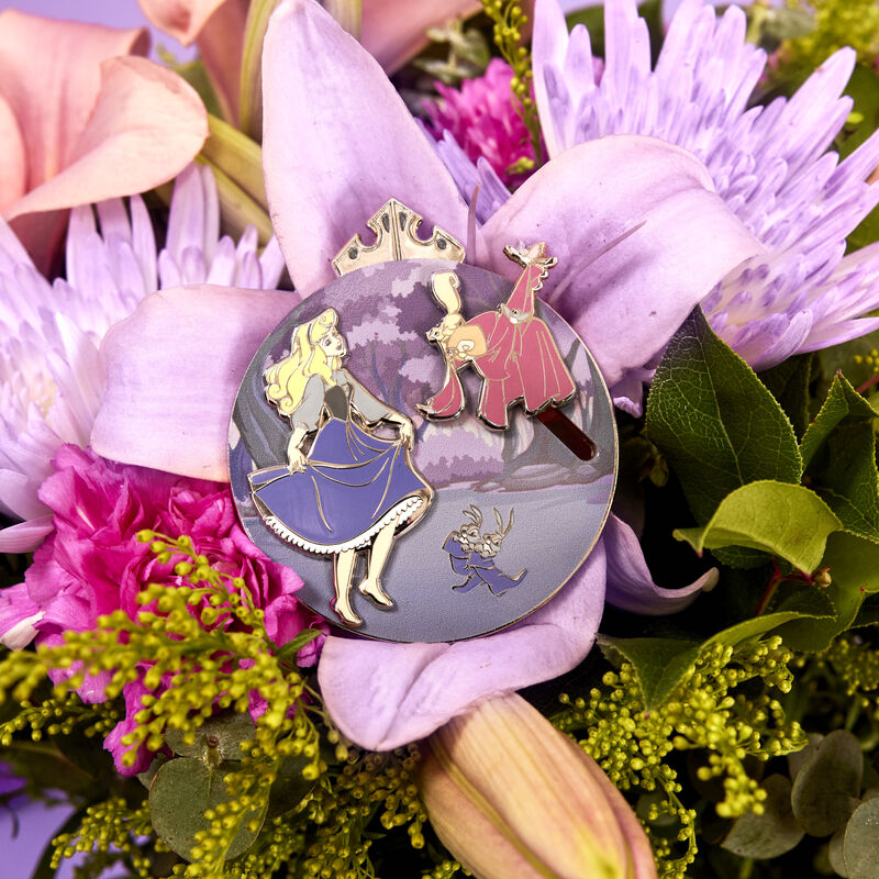 The Loungefly Disney Sleeping Beauty 65th Anniversary Floral Scene 3" Collector Box Sliding Pin sitting on top of a bouquet of flowers
